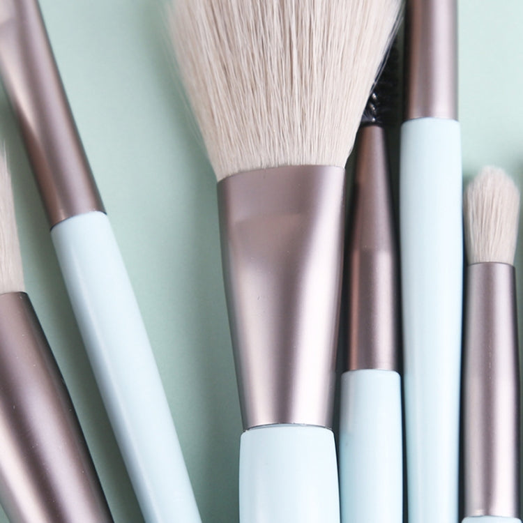 Close-up of mini makeup brushes with cream bristles and rose-gold metal stems