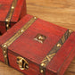 Red wooden jewelry box close-up: brass latch, studs, and top ornament