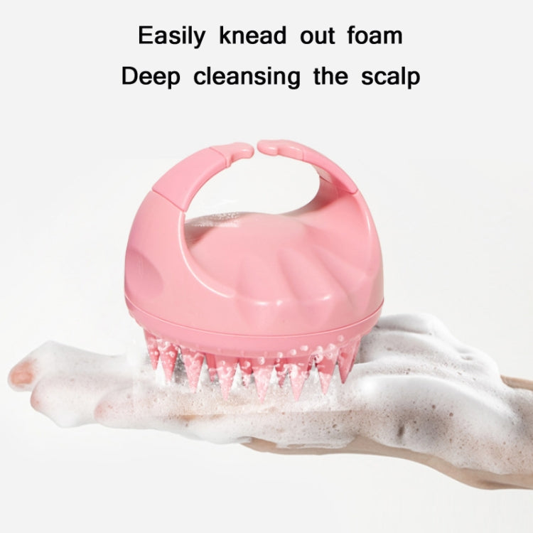 Pink silicone scalp brush used on hand with visible soap foam and bristles