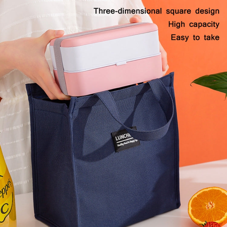 Navy insulated lunch bag holding a square lunch container with a pink lid