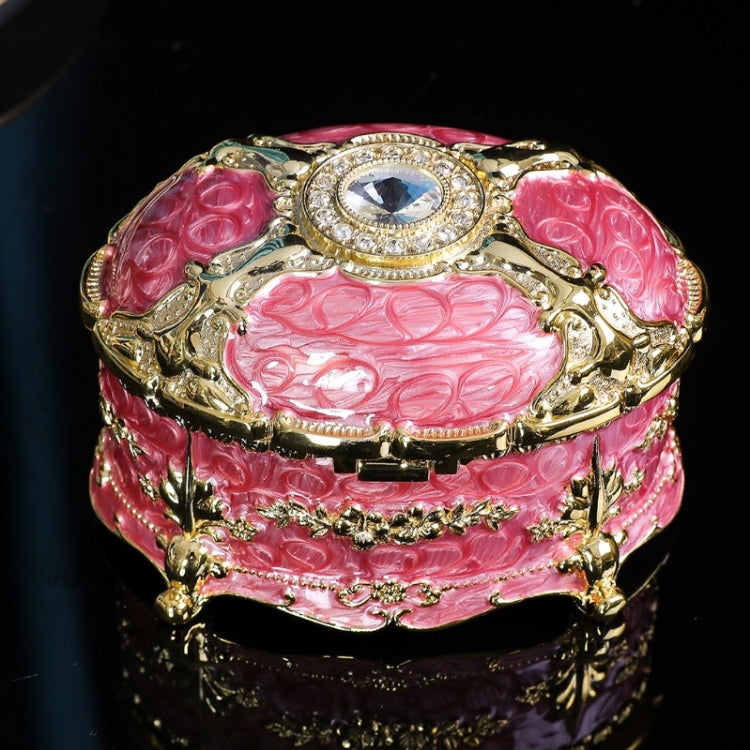 Gold-trim pink oval jewelry storage box with diamond-style center top and raised side filigree