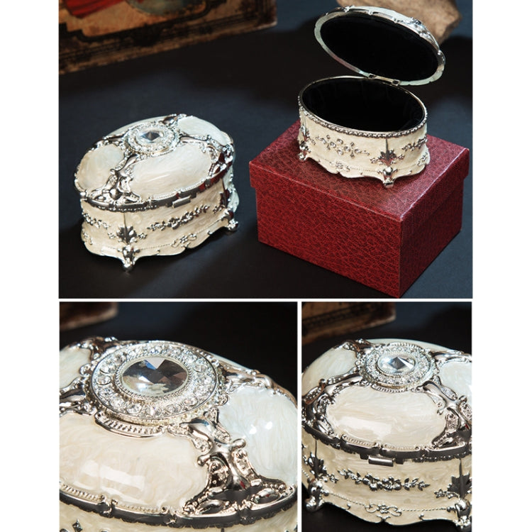 Oval jewelry storage box shown with open lid and dark interior inside a red gift box