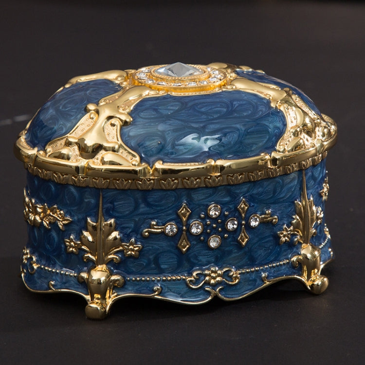 Gold-trim blue oval jewelry storage box with crystal-like top centerpiece and raised ornaments