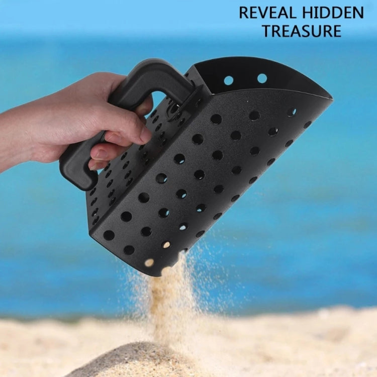Handheld perforated black sand scoop pouring sand, showing tool for metal detecting
