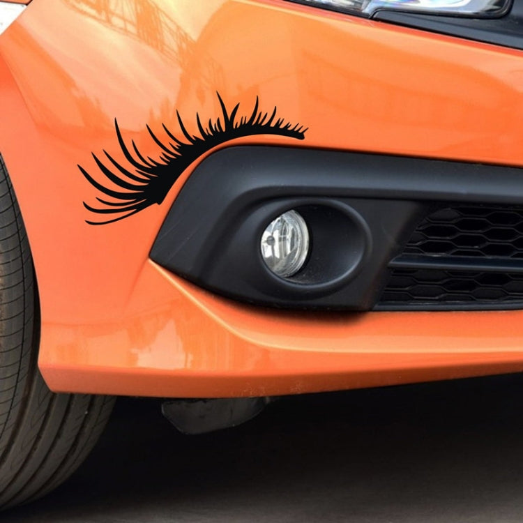 Black eyelash eyebrow headlight sticker on orange car front light.