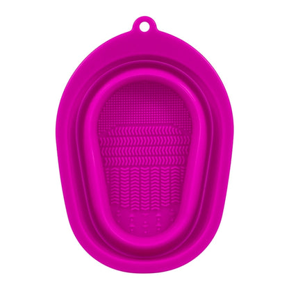Pink silicone makeup brush cleaning pad with oval loop and textured scrub surface.