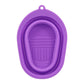 Purple silicone makeup brush cleaning pad with oval loop and textured scrub surface.