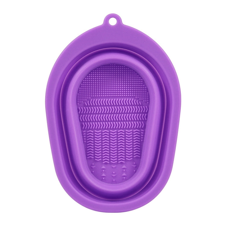 Purple silicone makeup brush cleaning pad with oval loop and textured scrub surface.