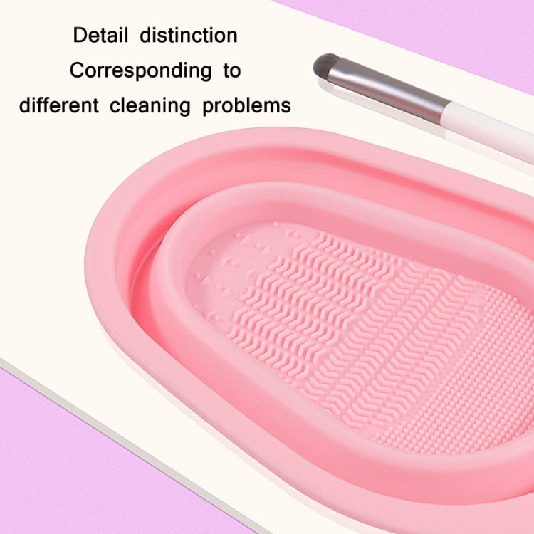 Pink silicone makeup brush cleaning pad with textured scrub ridges and resting brush.