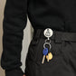 Retractable key ring on black belt with round silver disc and metal key loop
