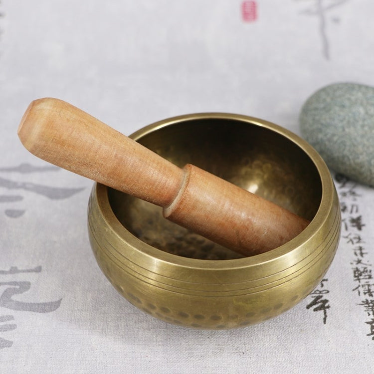 Buddha metal sound bowl with wooden mallet resting inside the bowl