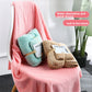 Pink coral fleece bath towel with smaller folded towels in blue and tan