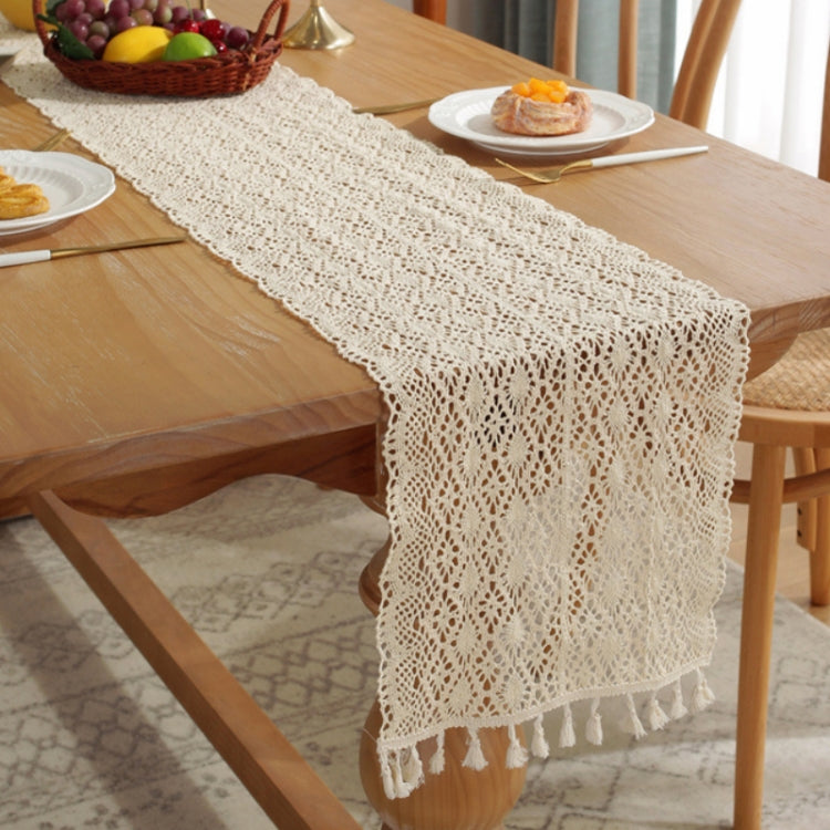 Cream crochet-style table runner draped with openwork pattern and tassel trim