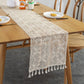 Cream openwork knitted table runner with repeating motifs and tassel trim detail