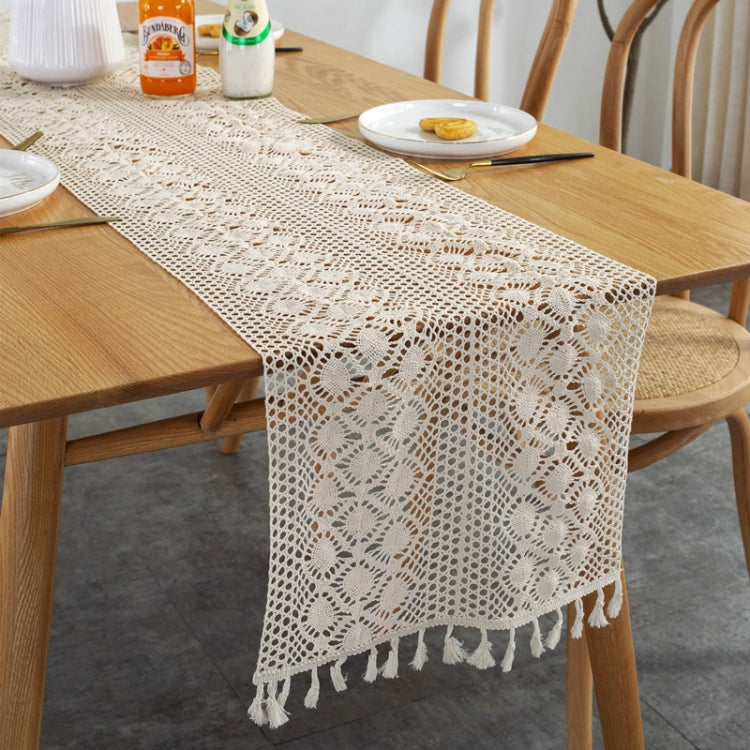 Cream lace table runner featuring openwork motifs and straight edge with fringe