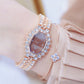 Rose-toned rhinestone quartz watch on wrist with brown dial and sparkling cuff bracelet