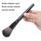 Powder makeup brush with soft dark bristles on a black handle, held in a hand