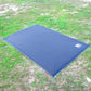Blue waterproof outdoor picnic mat spread on ground with corner stakes