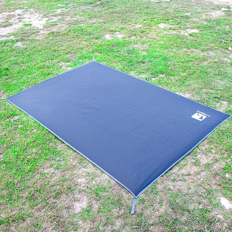Blue waterproof tent mat spread on uneven ground with corner stakes