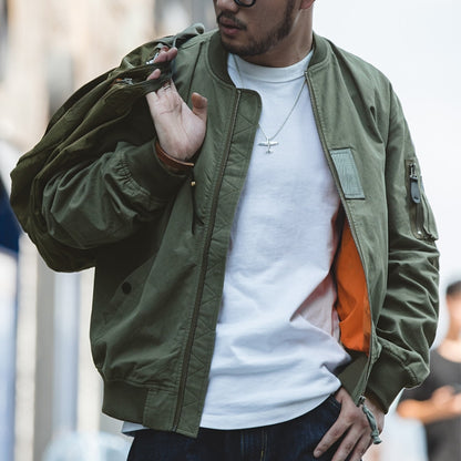 Green bomber jacket with zip front, ribbed collar, and utility sleeve pocket; orange lining
