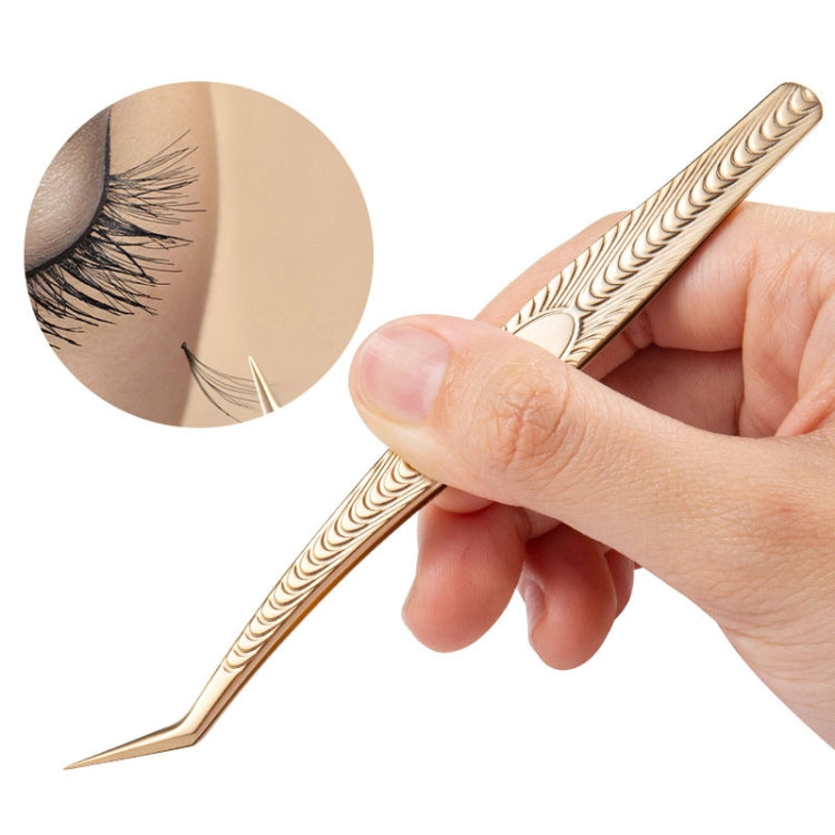 Gold eyelash tweezers held by hand, showing long etched handle and pointed end