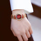 Ladies wrist watch on wrist with red dial and gold-and-silver patterned bracelet