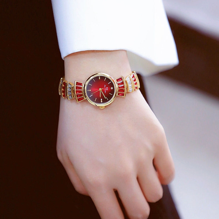 Ladies wrist watch on wrist with red dial and gold-and-silver patterned bracelet