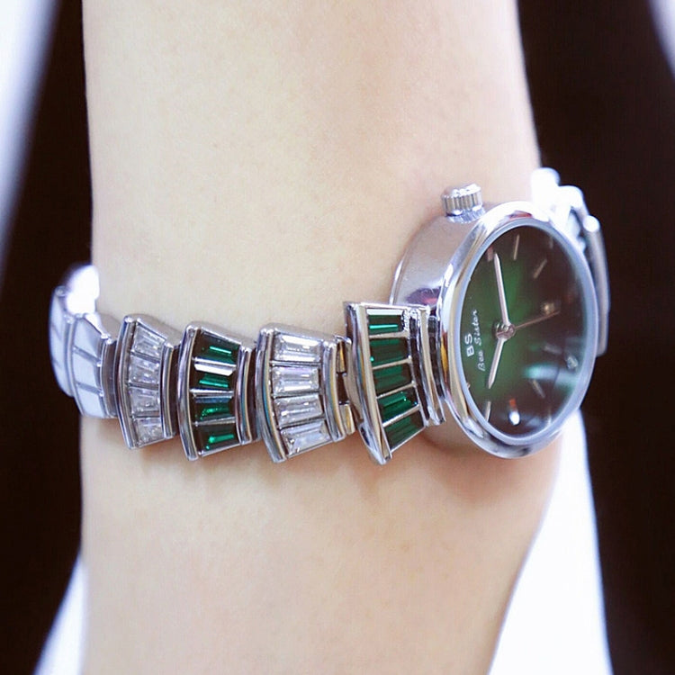 Ladies wrist watch on wrist with green dial, silver-tone case, and green stone accents