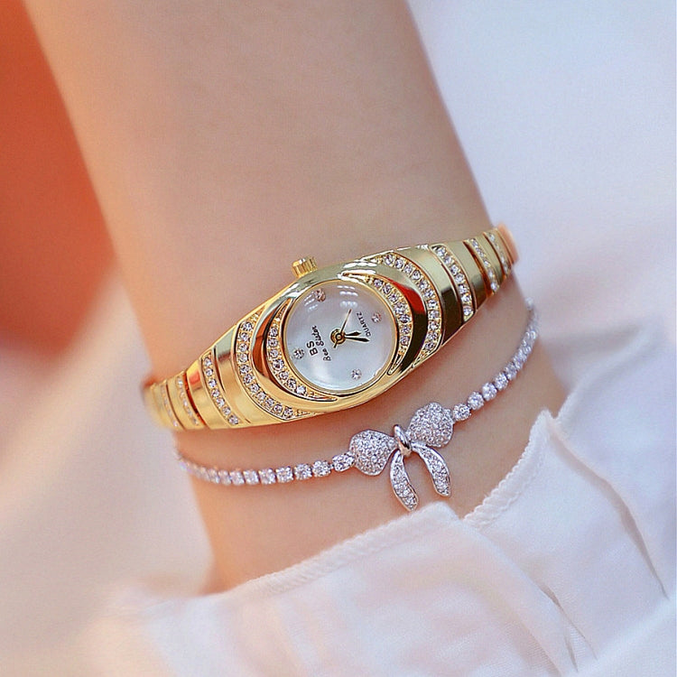Gold oval ladies watch with rhinestone bezel and link bracelet, worn on the wrist