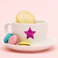 Purple glitter star sealing sticker on a white cup and saucer with treats