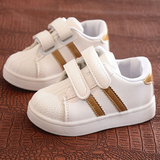 Kids white sneakers with gold side stripes and two hook-and-loop straps