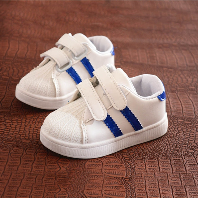 Children's white sneakers with blue side stripes and two-strap Velcro closures