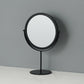 Desktop makeup mirror with round glass and black frame, on a black circular base