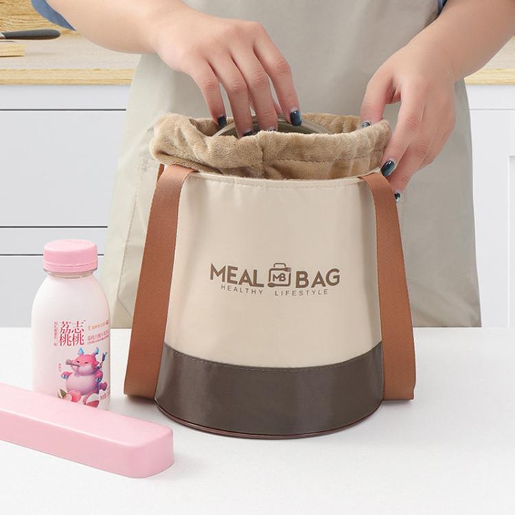 Person opening beige insulated lunch bag with drawstring and brown handles on top