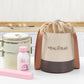 Beige round lunch bag with drawstring and handles, shown with other meal containers