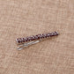 Red-and-silver swirl patterned tie clip with hinged clasp