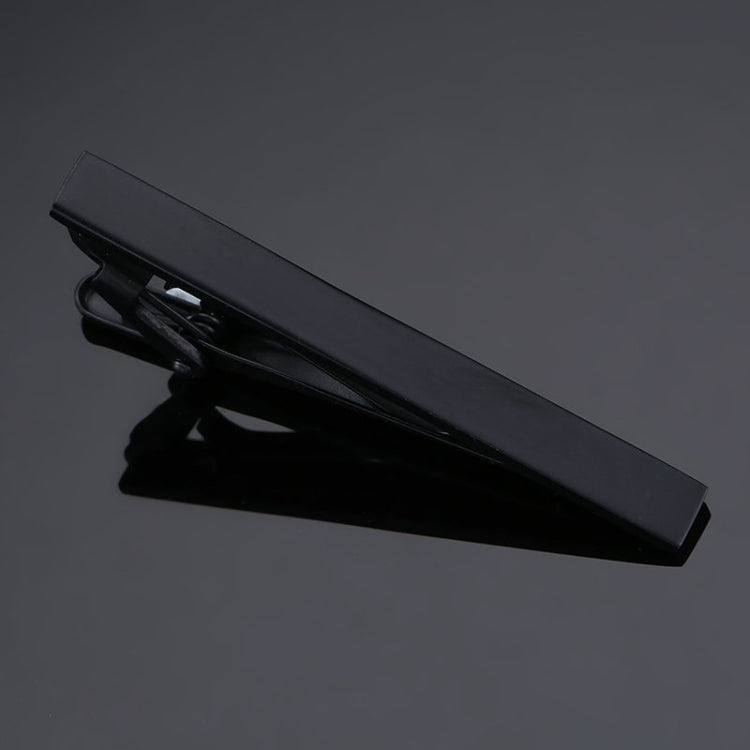 Black rectangular tie clip with minimal detailing and polished metal edges.