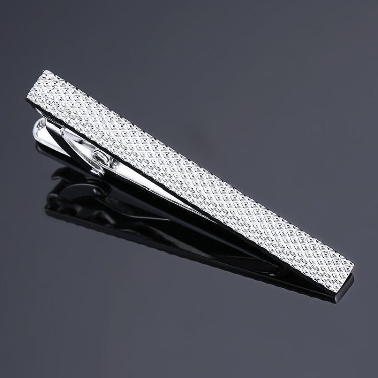 Textured silver tie clip with diamond pattern and polished metal clasp, hinged design.