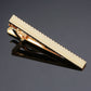 Gold tie clip with textured face and hinged clasp, glossy metal finish