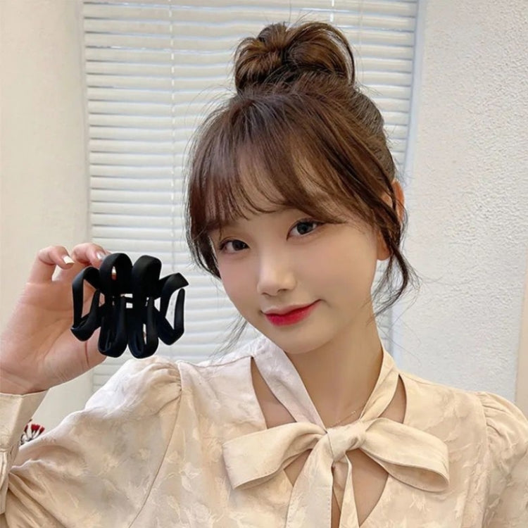 Black frosted claw hair clip set; model holds one clip by a bun