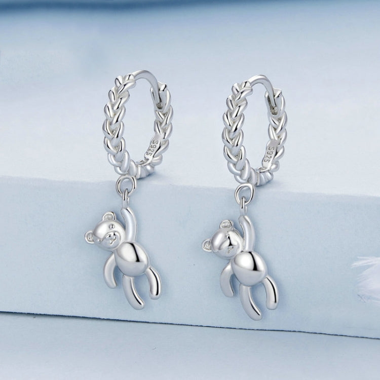 Silver-tone twist hoop earrings with dangling bear pendant and linked chain detail
