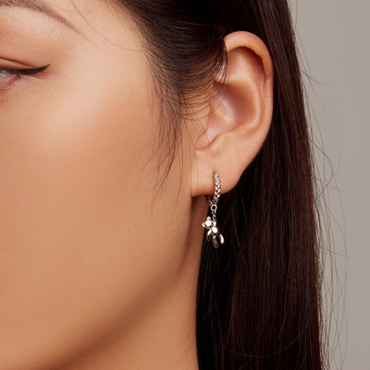 Bear charm hoop earrings worn on ear, silver-tone twist links with dangling pendant