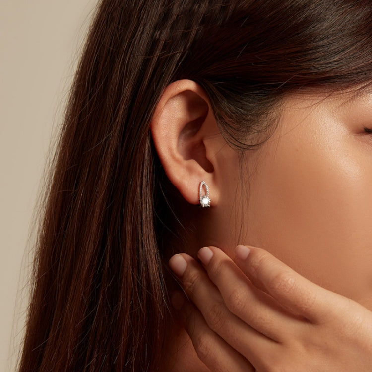 Sterling silver zirconia hoop earrings worn on ear, showing round center stone and halo