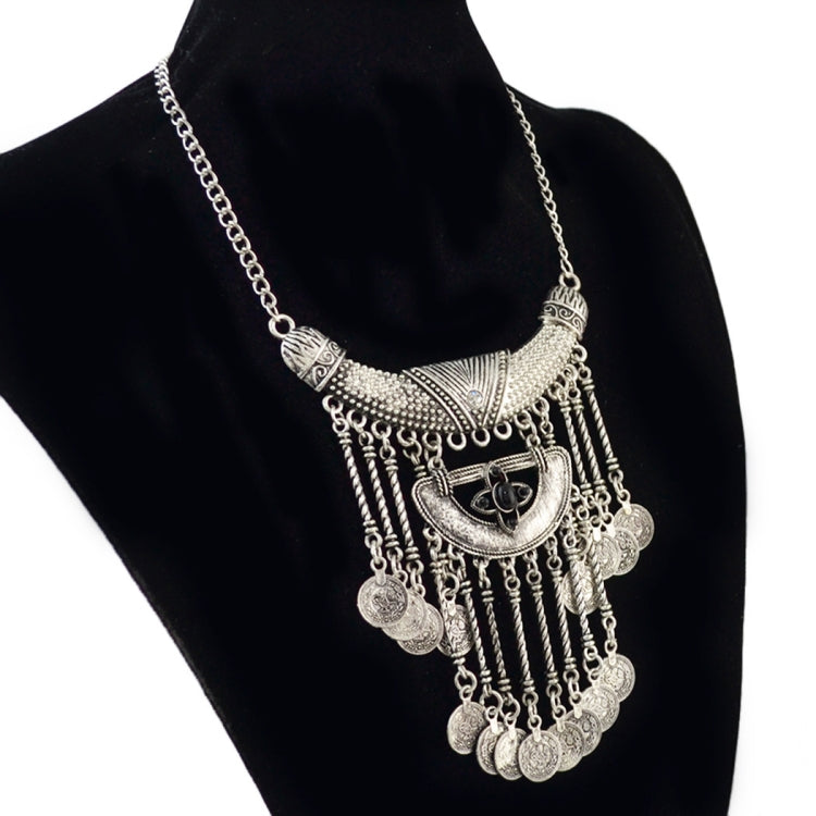 Tassel statement necklace with silver chain, ornate crescent bib, and dark center stone