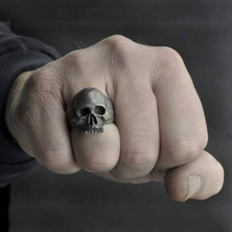 Skull ring on a hand, silver-tone with engraved teeth and hollow eye sockets