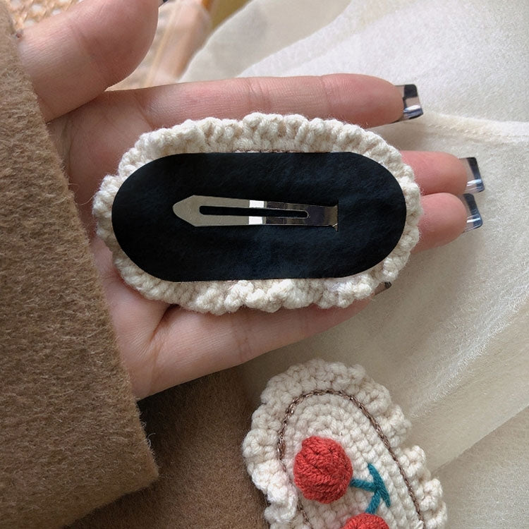 Black oval knit hair clip with silver snap bar and cream scalloped edge
