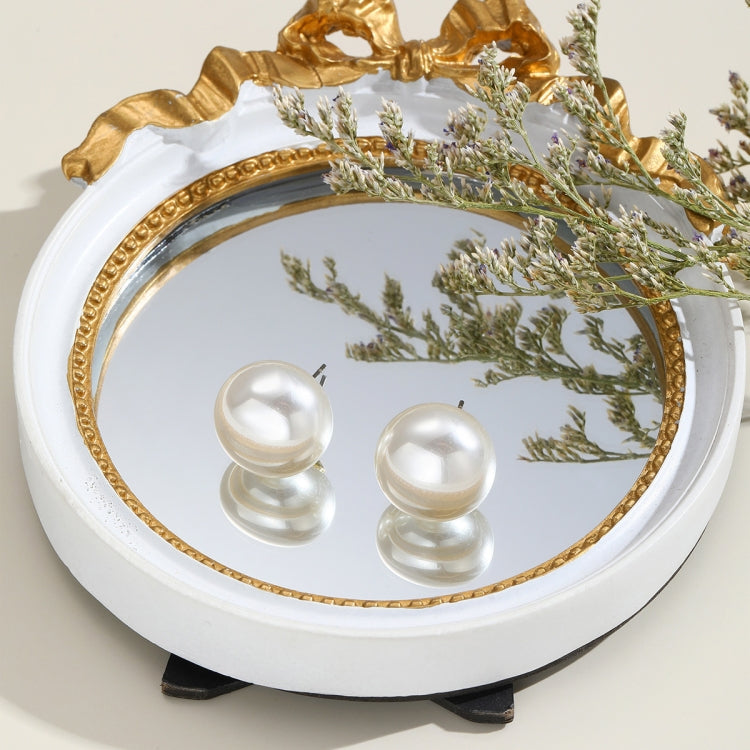 White pearl stud earrings with domed round fronts, shown in a decorative tray