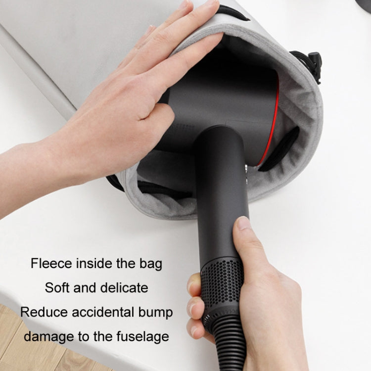 Open gray fleece-lined storage bag with hair dryer and nozzle being inserted.