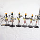 Set of man-shaped metal candlestick ornaments with colorful coiled bodies and trays