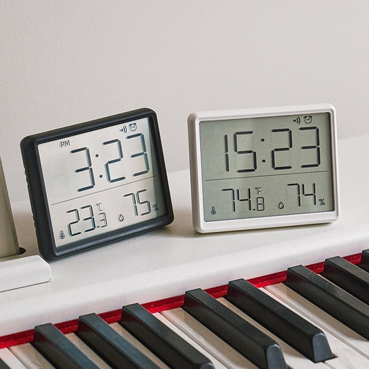 Magnetic digital clocks in black and white displaying time and temperature